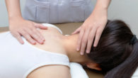 Girl is lying on the massage table while chiropractor checking her neck and spine