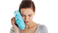 A girl is holding an ice pack after a tooth extraction