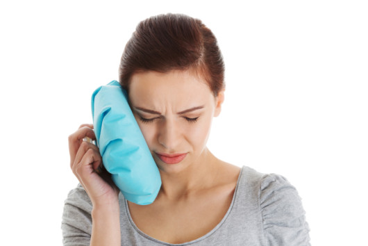 A girl is holding an ice pack after a tooth extraction