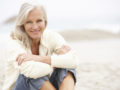 Senior Woman On Holiday Sitting On Winter Beach