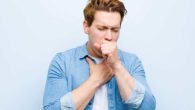 Man in blue t-shirt on blue background has deep coughing