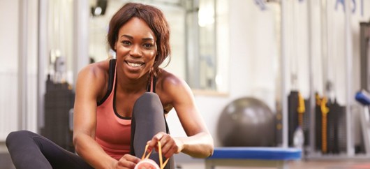 Girl in fitness outfit is sitting in the gym and smiling to the cam