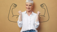 A young blonde girl in white blouse on brown background shows how confident she is