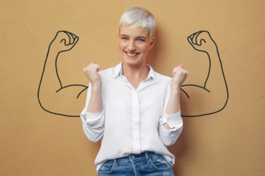 A young blonde girl in white blouse on brown background shows how confident she is