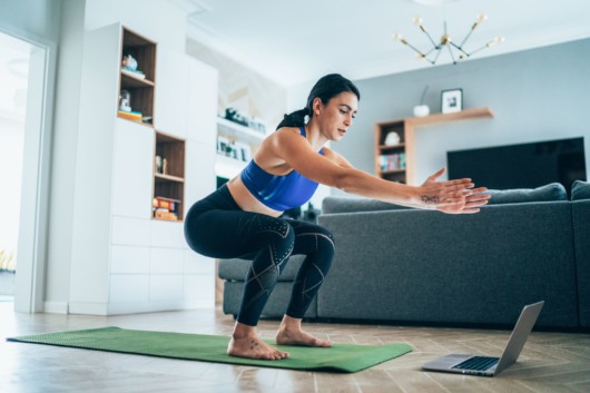 Girl is exercising at home in front of the laptop. Girl is doing home bodyweight workout 