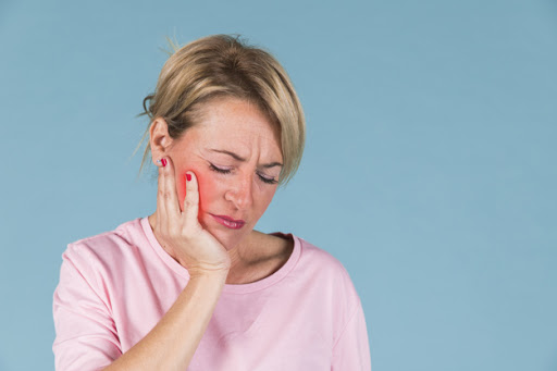 A girl with a tooth pain. A girl is holding her hand on her cheek because of the tooth pain