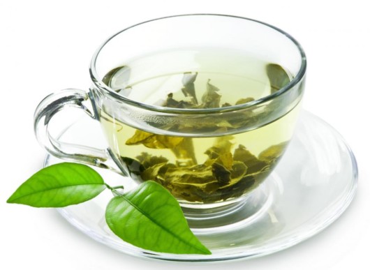 Green tee in a glass tea cup on the white table 