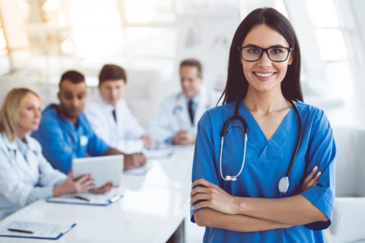 A girl in the doctor's outfit and stethoscope looks into the camera and smile