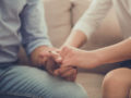 A man and a woman are holding hands in hands and sitting on the sofa