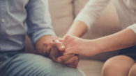 A man and a woman are holding hands in hands and sitting on the sofa