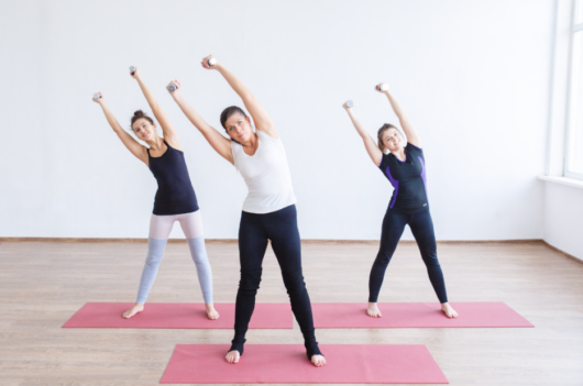 Girls are exercising in the room with dumbbells 