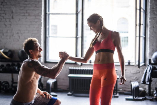 A girl and a woman are exercising in the gym and helping each other