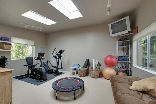 A room with fitness equipment and fitness gear, tv and sofa