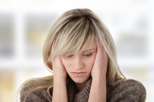 A blonde woman is depressed and holding her head with her hands