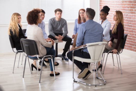 Men and women are sitting in circle in a rehab center to get help