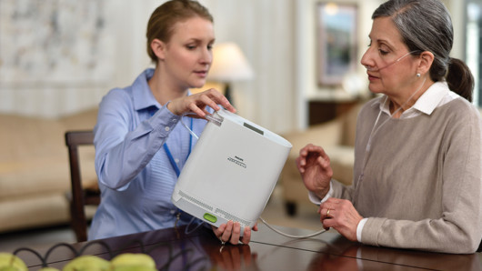 The girl is showing an old woman the room how oxygen generator works