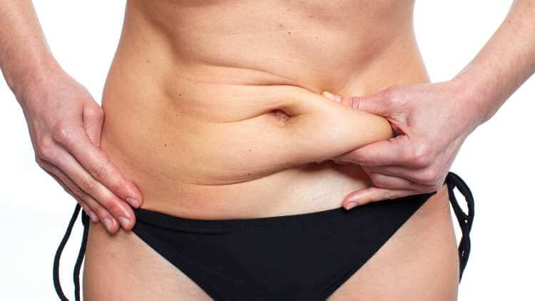 The girl in black underwear pinches her belly to show loose skin. The girl shows how much belly fat she has