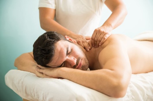 A handsome man is lying on the white bed at the massage 