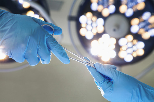 two surgeons in blue gloves are holding the scissors in the surgeon room