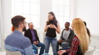 A young girl stands and talking in front of the people in the rehab