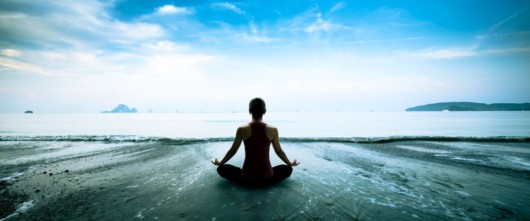 Girl is sitting in lotus pose on the beach