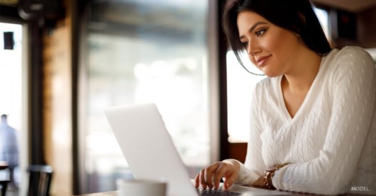 The girl is researching the surgeon in the internet before she makes a cosmetic procedure