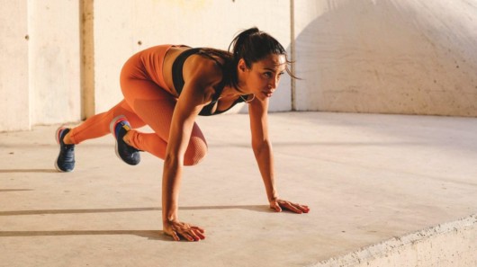 A woman in sportswear doing HIIT workout exercise the floor