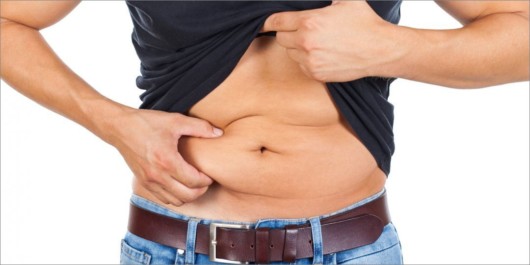 A man in black shirt on white background is showing his big belly and loose skin