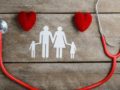 Two hearts, stethoscope and family image are on the wooden background