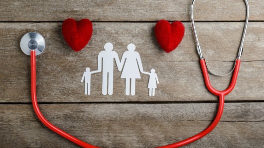 Two hearts, stethoscope and family image are on the wooden background
