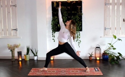 Girl in white top and black leggings are dong yoga in the room