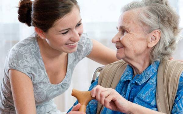 A young lady is smiling at an old lady