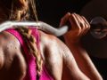 Girl in pink sports bra with barbell on her shoulders ready to workout