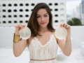 A girls in white dress holding the breast implants in her hands