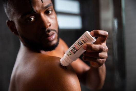 A black man putting CBD cream on his shoulder as a post recovery