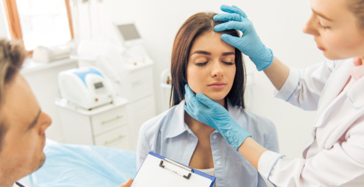 A doctor examining the woman's face after the plastic surgery