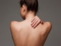 The beautiful woman showing her back on gray background