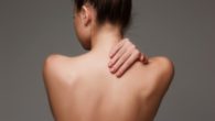 The beautiful woman showing her back on gray background