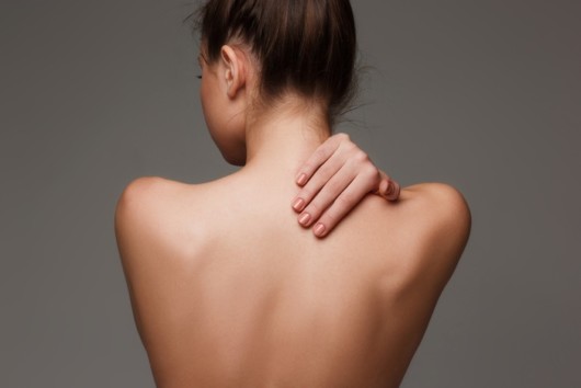 The beautiful woman showing her back on gray background