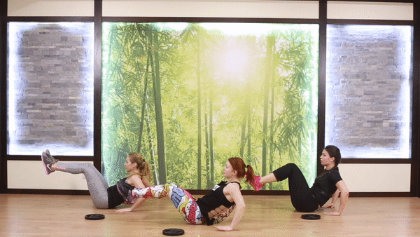 Three girls in sporty outfit doing supported v-sit up exercise on the floor. Girls perform fat blast workout to burn fat and lose weight