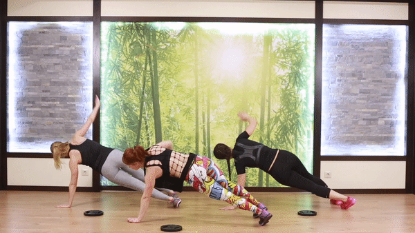 Three girls in sporty outfit doing t-plank exercise on the floor. Beautiful girls do fat blast workout to burn fat and lose weight