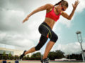 A fit and beautiful girl in a sporty outfit and glasses is does interval training on the stadium