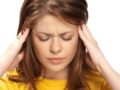 A beautiful girl in yellow sweater is touching her head with both hands trying to cope with dizziness