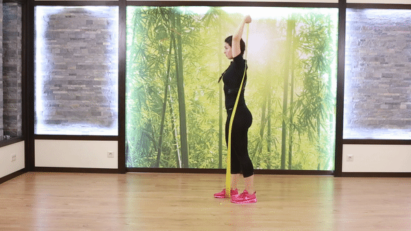 A beautiful girl in black sport outfit and pinky sport shoes doing Resistance Band Overhead Triceps Extension Exercise in the room