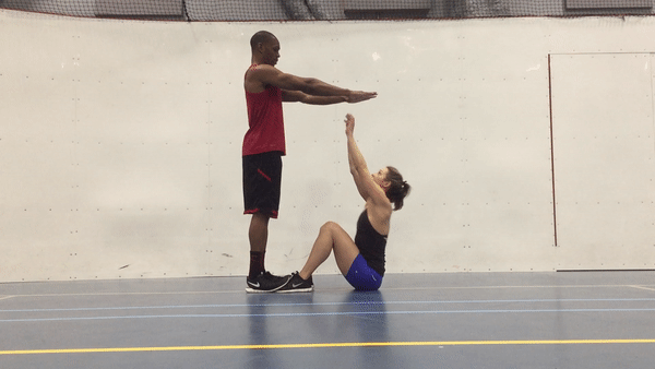 A fit woman and man are doing sit up taps exercise in the gym for strong abs.