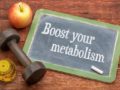 A black board on wooden background with the a sentence "boost your metabolism" written on it