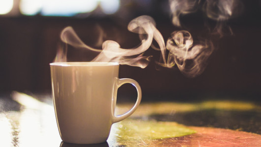 White cup with hot coffee on the table 