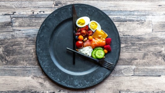 A black plate with food on is shows the eating window of intermittent fasting