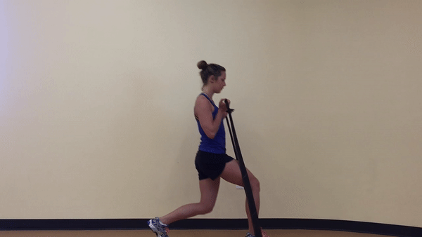 A beautiful and fit girl in blue top and black shorts is doing Lunge Step-in with resistance band in the room.