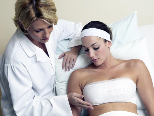 Doctor is checking how the girl who did breast reduction operation is recovering